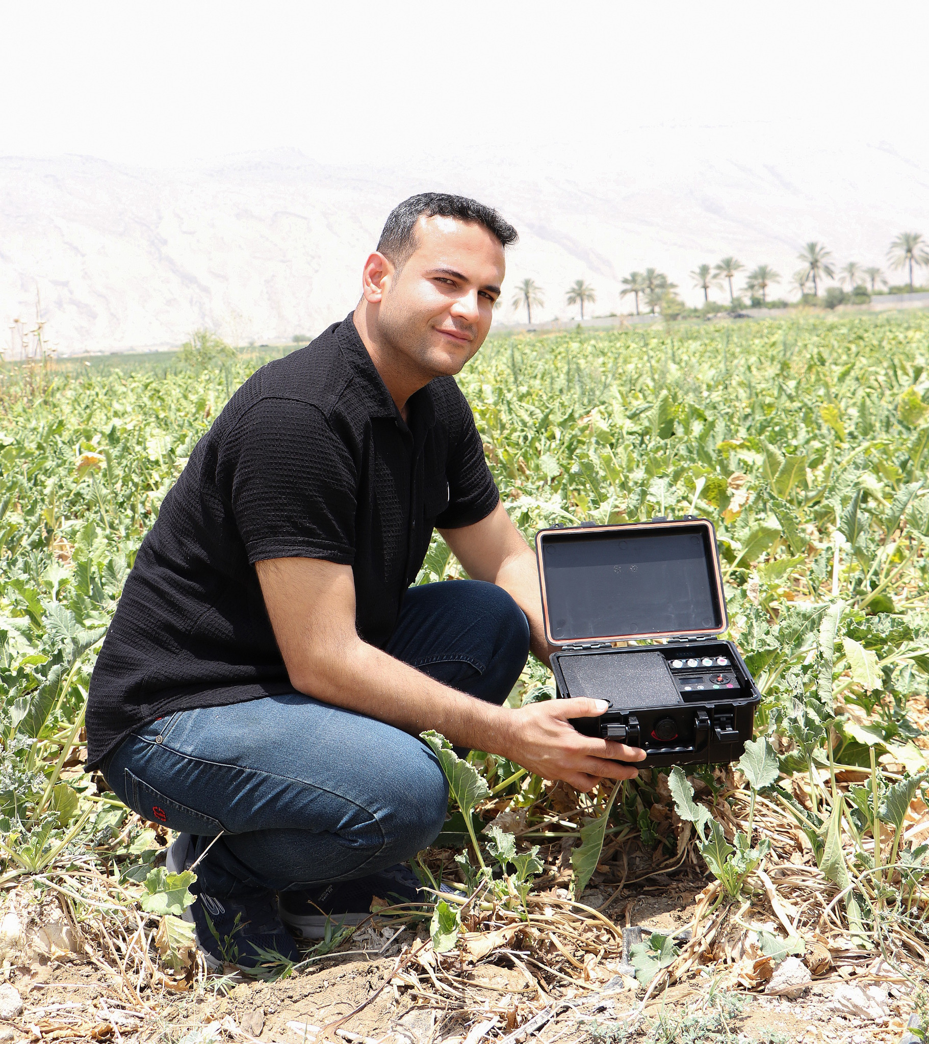 A member of the ASAD team presenting the soil-testing device in a cultivated field